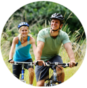 A man and woman riding bikes through the grass.